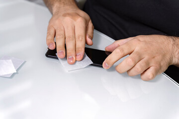 Cleaning smartphone screen with alcohol wipe to install protective glass. changes the protective glass on phone