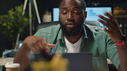 Focused afro business man discussing project by video chat in night office