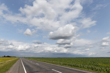 road among the fields under the sky with clouds