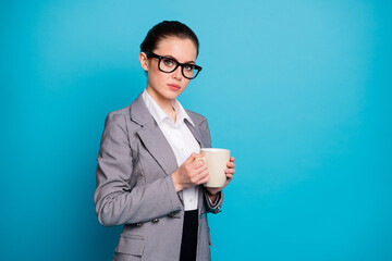 Photo of confident girl financier hold hot cappuccino cup wear grey blazer suit isolated over blue...