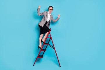 Fototapeta premium Full length photo agent girl climb career ladder raise fists scream wear jacket skirt isolated blue color background