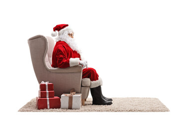 Profile shot of santa claus sitting in an armchair with presents next to him