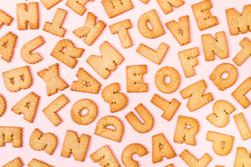 Galletas de letras sobre un fondo rosa liso. Vista superior 