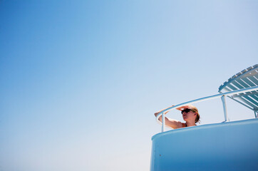 Obraz premium Young woman looking out from a boat on a clear summer day.