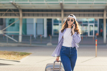 Fototapeta premium A young beautiful girl student leaves the airport in a new city, and waits for a taxi