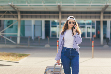 Fototapeta premium A young beautiful girl student leaves the airport in a new city, and waits for a taxi