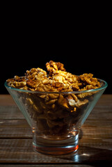 Peeled walnuts in a bowl. Nuts close up on an old wooden board. Food on a shabby table. Contrasting dramatic light as an artistic effect.