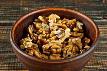 Peeled walnuts in a bowl. Nuts close up on an old wooden board. Food on a shabby table.