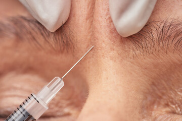 Beautician giving an injection to female wrinkle