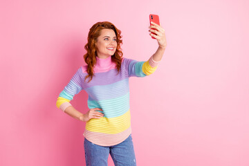 Photo portrait of woman taking selfie with phone in one hand isolated on pastel pink colored background
