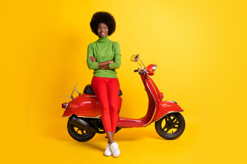 Fototapeta na wymiar Photo portrait of brunette african american woman biker on motorbike isolated on vivid yellow colored background