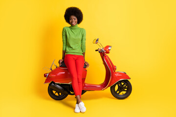 Fototapeta na wymiar Photo portrait of young woman leaning on scooter isolated on vivid yellow colored background