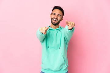 Young caucasian man isolated on pink background surprised and pointing front
