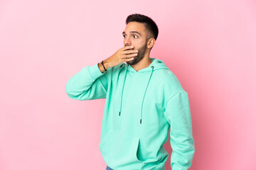 Young caucasian man isolated on pink background doing surprise gesture while looking to the side