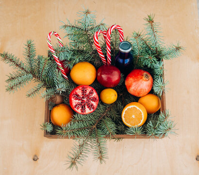 Christmas composition in a wooden basket with fruits, lollipops and a Christmas tree on a blue background