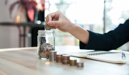 saving money with hand putting coins in jug glass concept financial
