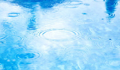 Stains circles on water from rain. Raindrops on pool blue water surface. blue water texture as background.