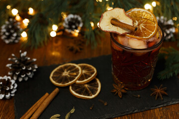 Delicious traditional mulled wine in glass with cinnamon stick and dried orange arranged on sate...