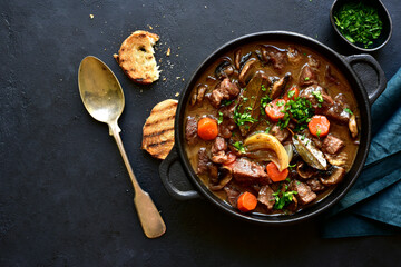 Beef bourguignon - meat stew with vegetables and mushrooms with red wine, traditinal dish of french cuisine. Top view with copy space.