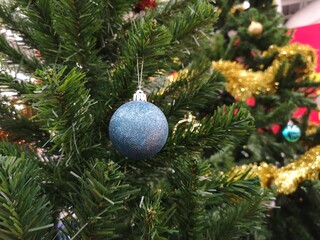 Decorated Christmas green tree decorations have blue ball, gold leaves on blurred of background