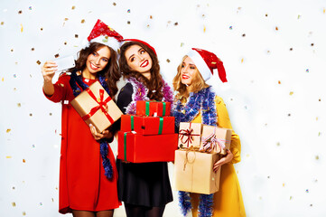Selfie time. Three Christmas young women with presents make selfie posing on white background. Happy party moments. Winter holiday.
