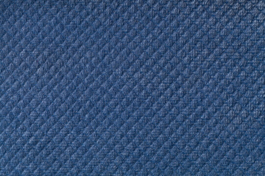 Texture of navy blue fluffy fabric background with rhomboid pattern, macro.