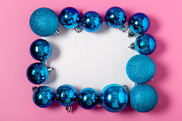 Frame made of blue Christmas balls and white blank paper with copy space on a pink background. christmas and new year celebration concept. flat lay, mockup, top view.
