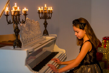 Beautiful Girl Playing Piano Decorated with Candles in Candlesticks.