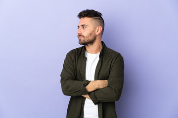 Caucasian man isolated on purple background keeping the arms crossed