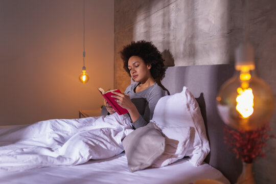 Woman lying in bed reading a book