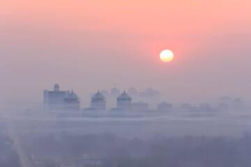 Blurred outlines of the city at dawn in smog
