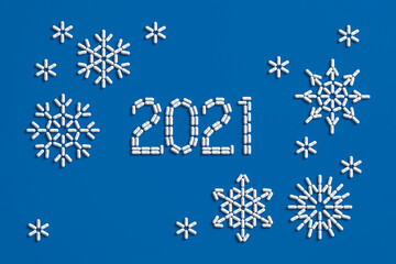 Medical concept congratulations on the year 2021. A lot of pills scattered on a blue background in the form of the number 2021 and snowflakes. 3D illustration