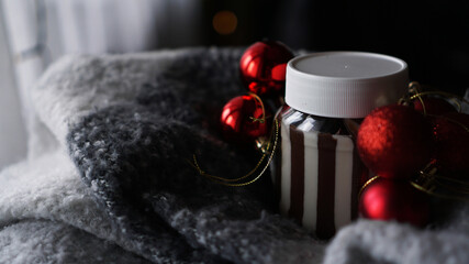 Sweet chocolate cream in the jar against Christmas background with red balls