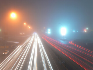 Fototapeta na wymiar View of the night street in the fog with the burning street lamps and motorway tracks