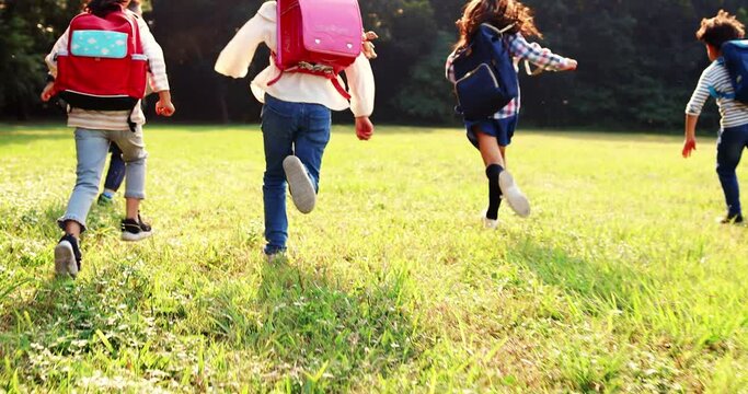 rear view of elementary school kids running on the grass