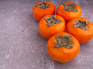 Side view of persimmons on a gray stone background with copy space for text. Concept of health fruit