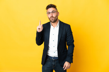 Businessman over isolated yellow background intending to realizes the solution while lifting a...
