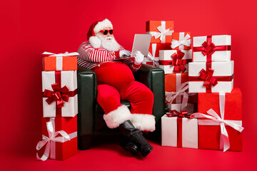 Photo of santa claus sit armchair use netbook wear x-mas costume suspenders cap eyewear isolated...
