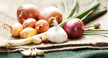 Onions, leek and garlic on jute, copy space