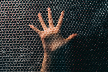 Social anxiety. Panic attack. Nervous breakdown. Fear tense. Desperate insecure woman hand trying to find way out trapped behind plastic bubble wrap textured wall in darkness.