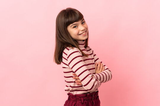Little girl isolated on pink background with arms crossed and happy