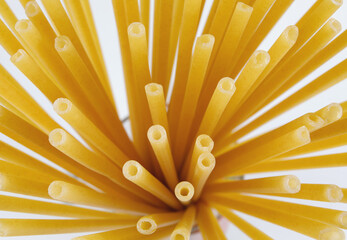 Long tubular pasta diverge with a fan from one point, a top view.