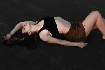 
A beautiful girl in a tank top and a skirt lies on the roof