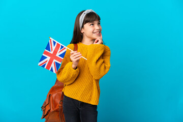 Little girl studying English isolated on blue background thinking an idea while looking up