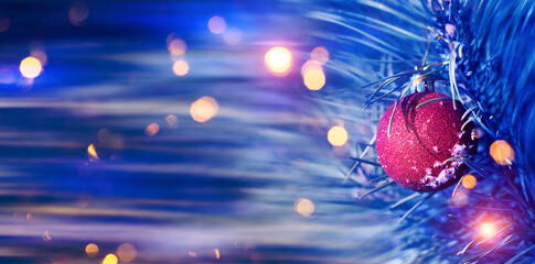Blurred festive Christmas background. Pine branch with balls close-up, blurry bokeh lights,...