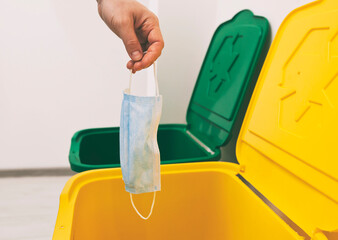 The woman throwing the medical mask into one of three trash bins