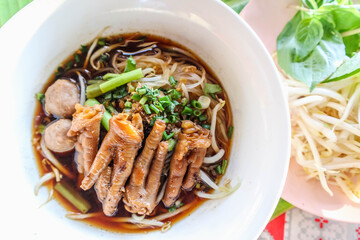 Delicious chicken feet noodles in a white plate with vegetables