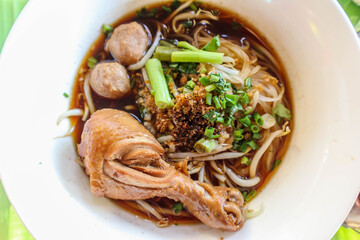 Close-up chicken legs with noodles and vegetable in dish.