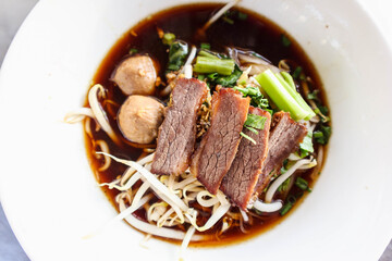 Close-up beef noodles with fish ball and vegetable in dish.