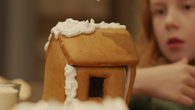 Closeup of decorating gingerbread house with crusting buttercream on Christmas Eve